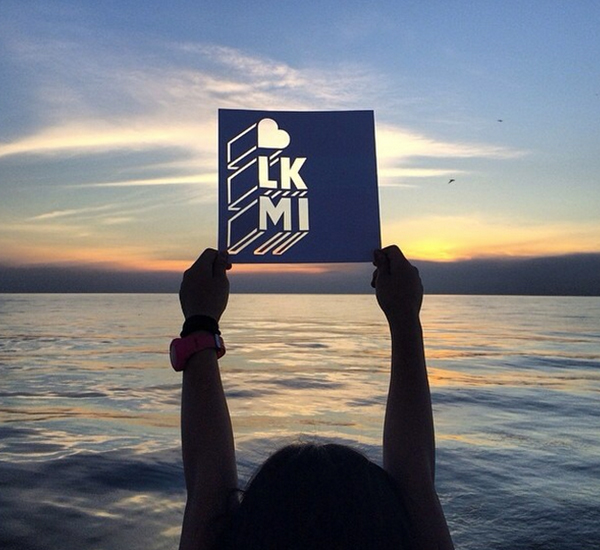 Person at Lake Michigan holding up photo frame at sunset