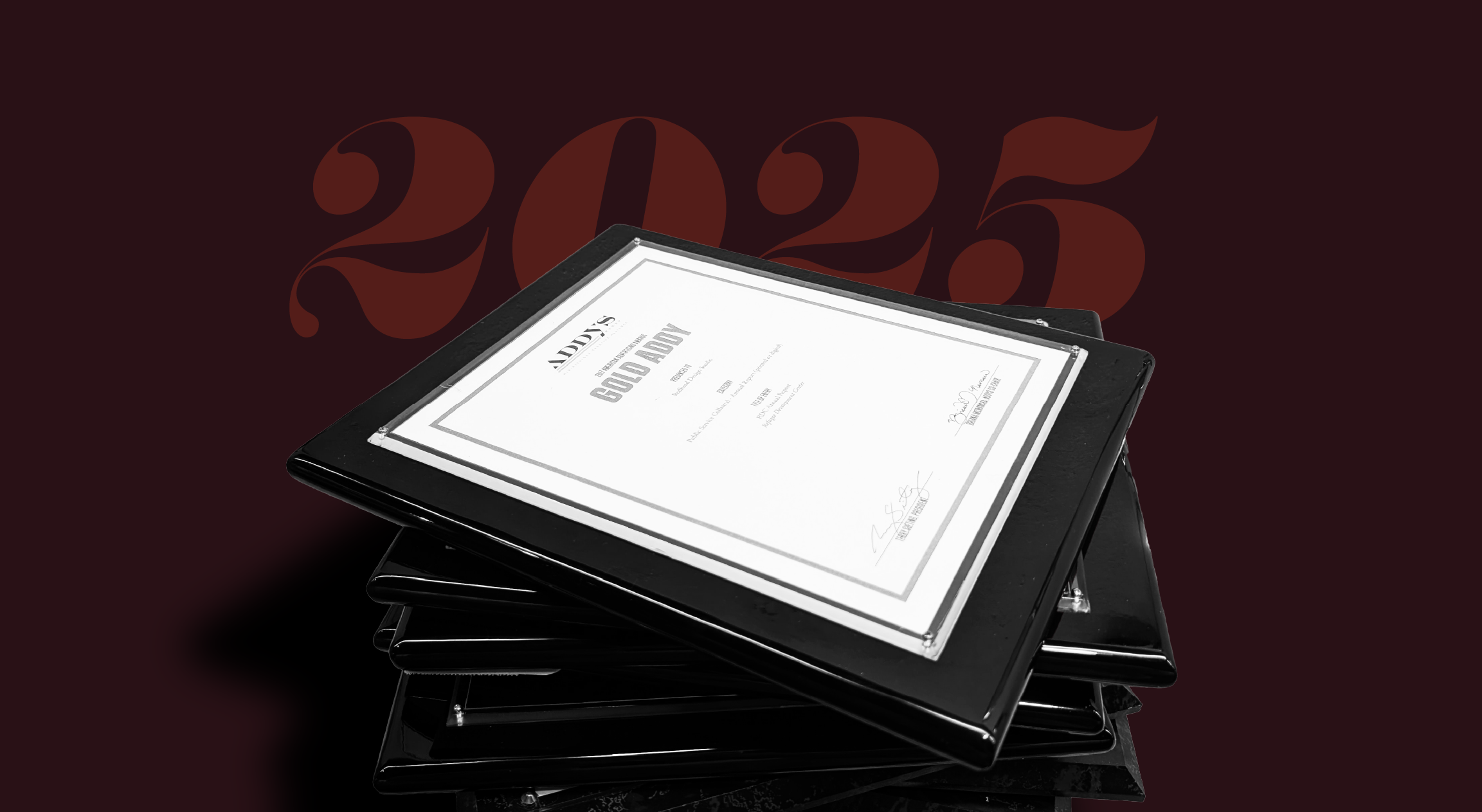 A stack of ADDY awards in plaques is displayed in front of a brown background that reads "2025." 