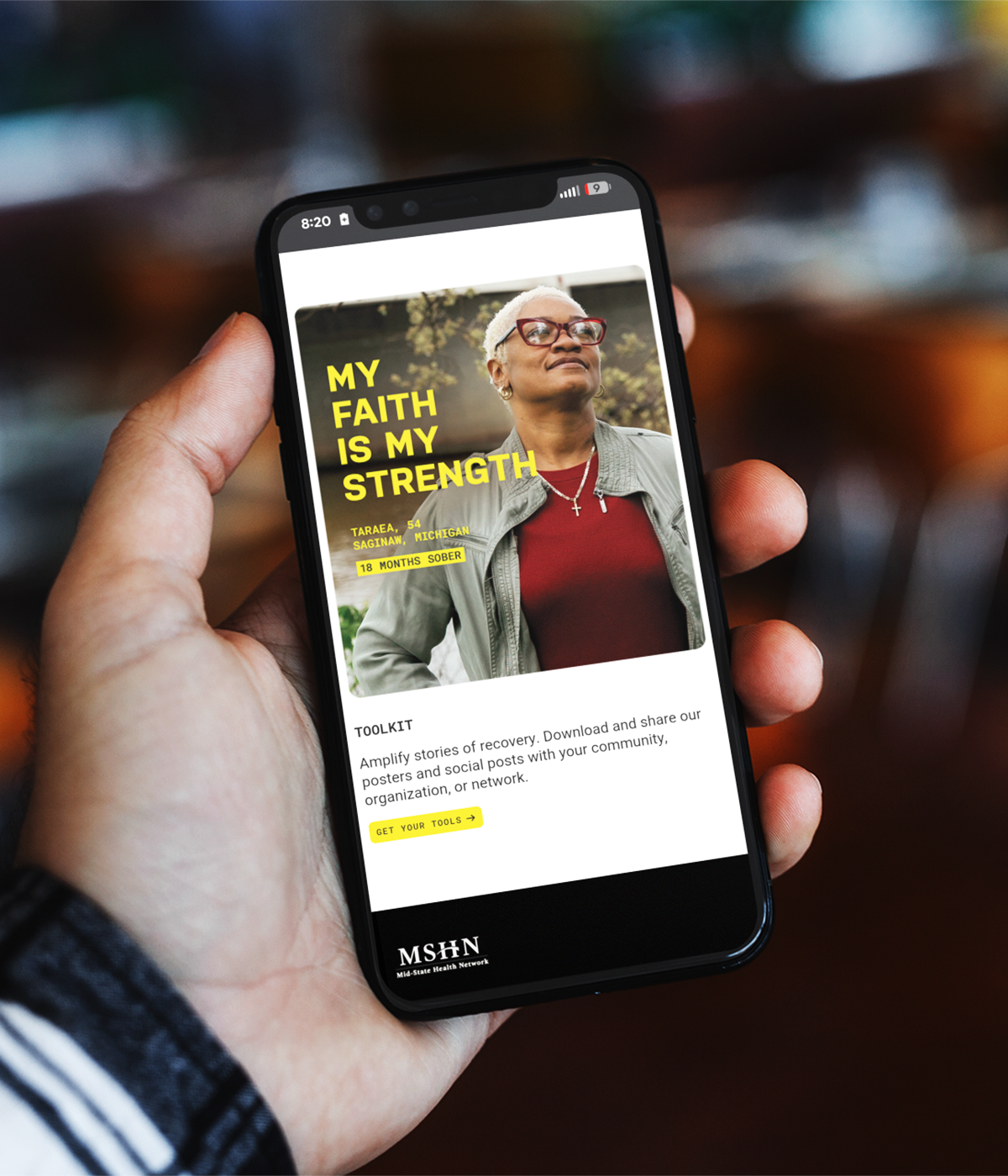 A mobile phone shows a social media post that reads "My faith is my strength."