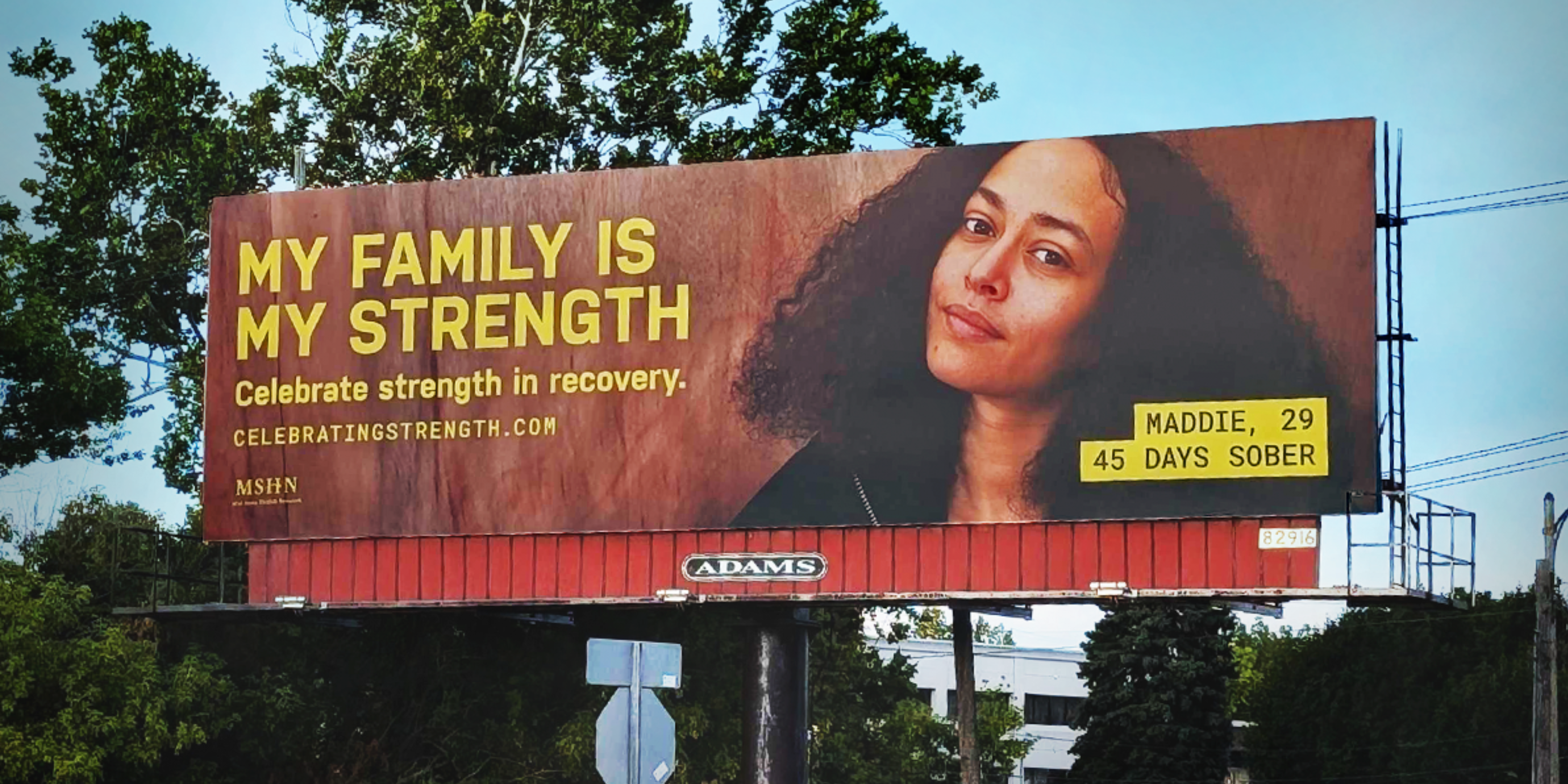 A billboard shows a portrait of a woman with the text "My family is my strength"