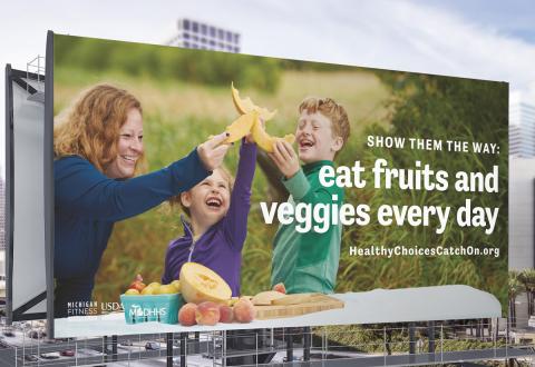 Billboard of mom and kids eating cantaloupe that says, "show them the way eat fruits and veggies every day."